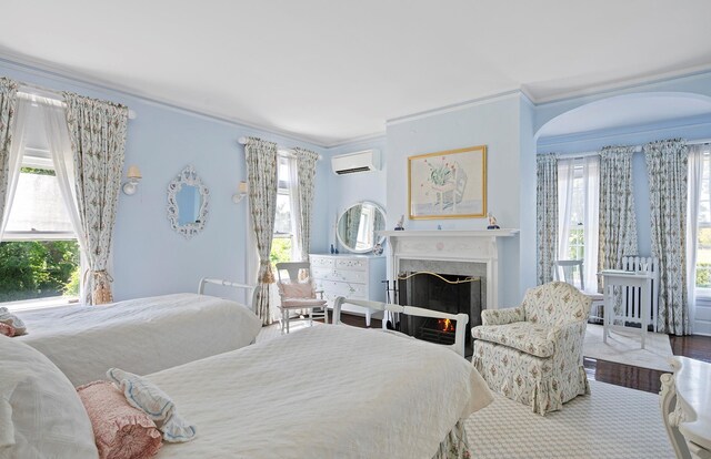 107 Quogue St, Quogue, NY 11959 - bedroom featuring ornamental molding, a wall mounted AC, a premium fireplace, and wood finished floors