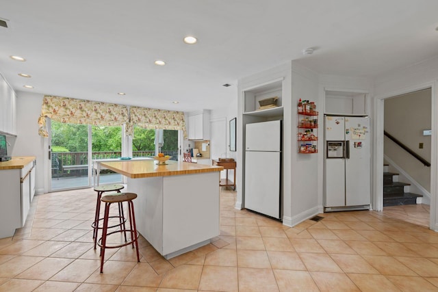 24 Wellington Rd, Locust Valley, NY 11560 - kitchen with white refrigerator with ice dispenser, freestanding refrigerator, wooden counters, white cabinets, and light tile patterned flooring