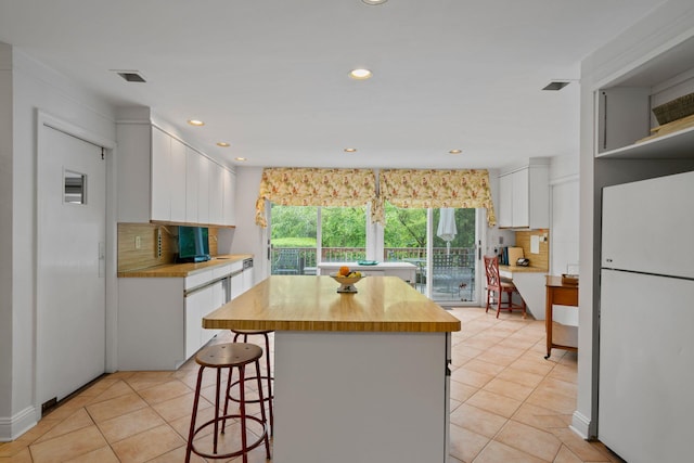 24 Wellington Rd, Locust Valley, NY 11560 - kitchen featuring freestanding refrigerator, light tile patterned floors, white cabinetry, backsplash, and recessed lighting