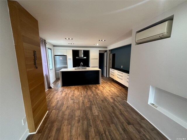 9-01 127th St, College Point, NY 11356 - kitchen with an AC wall unit, a sink, freestanding refrigerator, a center island with sink, and dark wood-style flooring
