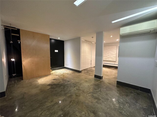 9-01 127th St, College Point, NY 11356 - empty room with a wall unit AC, concrete flooring, a baseboard radiator, baseboards, and a barn door