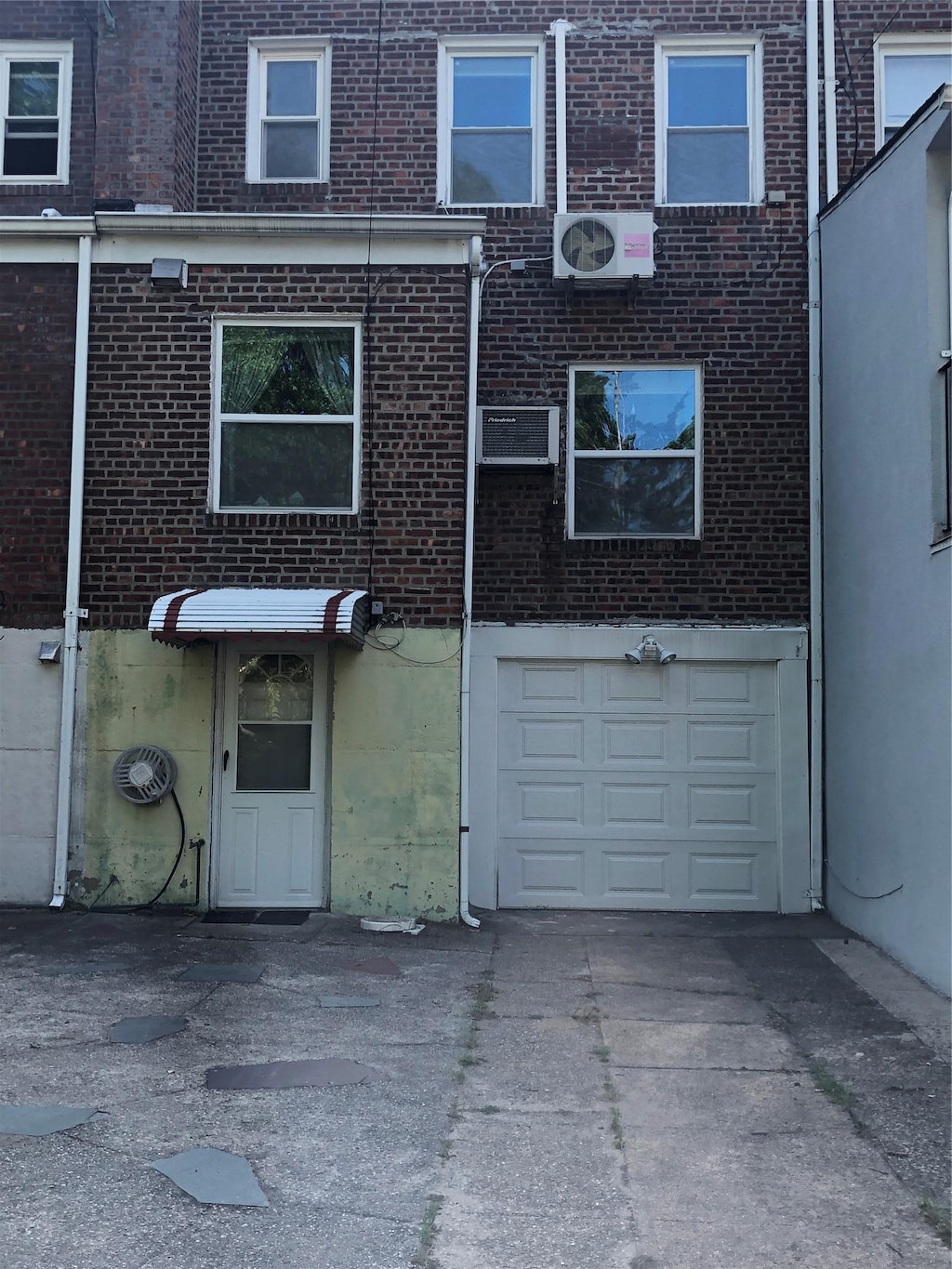70-27 175th St, Fresh Meadows, NY 11365 - back of house with brick siding, an attached garage, driveway, and a cooling unit