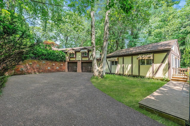 114 Oakwood Dr, Wading River, NY 11792 - tudor home featuring driveway, an attached garage, a front yard, stucco siding, and a deck