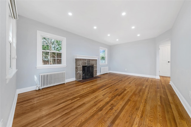 1779 Aladdin Ave, New Hyde Park, NY 11040 - unfurnished living room featuring radiator heating unit, healthy amount of natural light, wood finished floors, a stone fireplace, and recessed lighting
