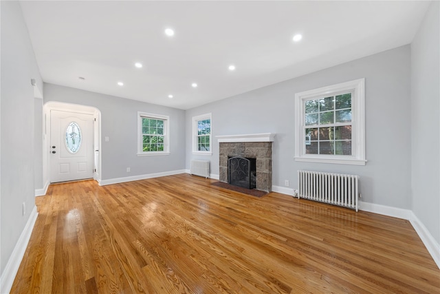 1779 Aladdin Ave, New Hyde Park, NY 11040 - unfurnished living room featuring radiator, a fireplace, light wood-style floors, baseboards, and recessed lighting