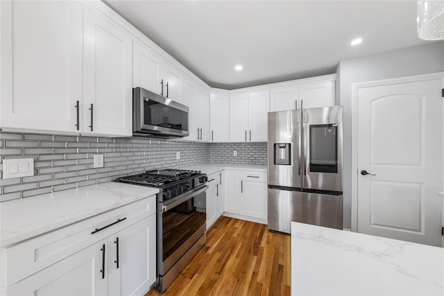 1779 Aladdin Ave, New Hyde Park, NY 11040 - kitchen featuring appliances with stainless steel finishes, light wood finished floors, white cabinetry, light stone countertops, and recessed lighting