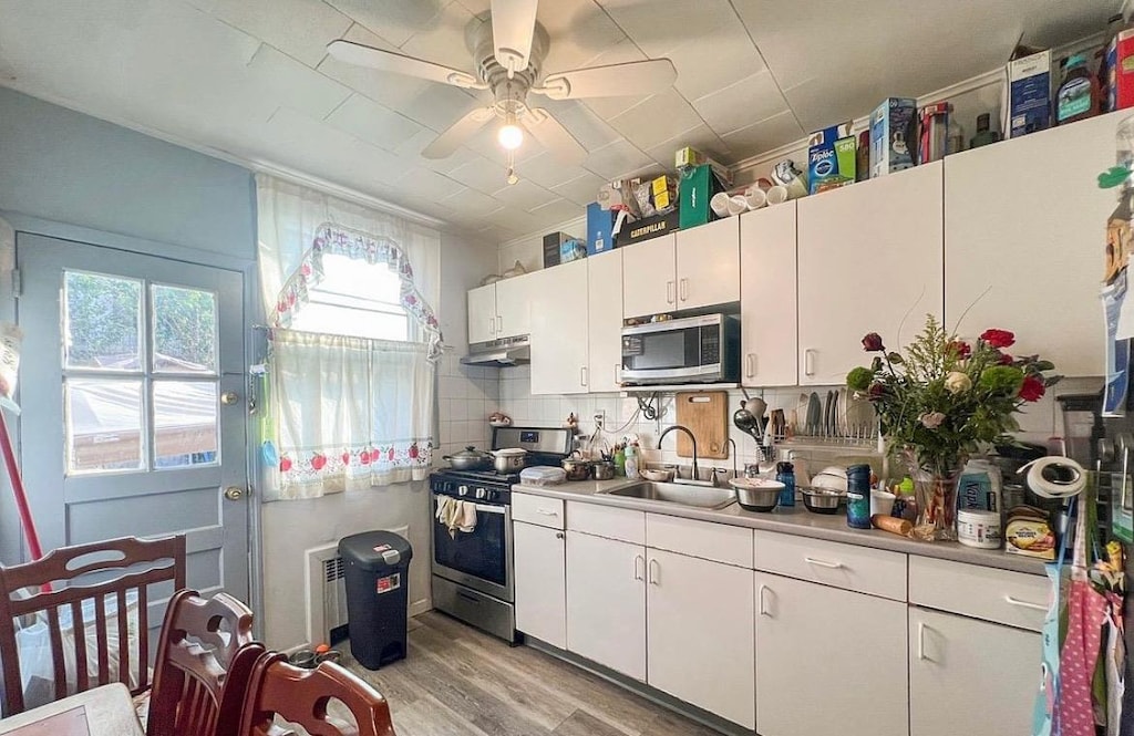 1230 59th St, Brooklyn, NY 11219 - kitchen featuring appliances with stainless steel finishes, a sink, under cabinet range hood, and white cabinets