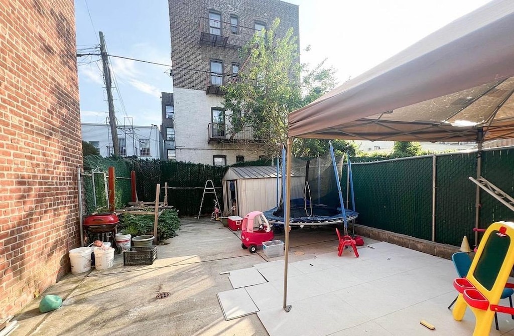 1230 59th St, Brooklyn, NY 11219 - fenced backyard featuring a patio and a trampoline