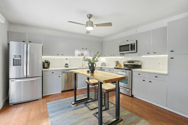963 Heritage Hls Unit C, Somers, NY 10589 - kitchen featuring appliances with stainless steel finishes, backsplash, a ceiling fan, light countertops, and wood finished floors