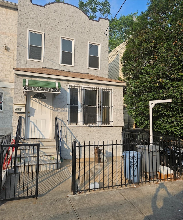 495 Milford St, Brooklyn, NY 11208 - view of front of house with a fenced front yard, stucco siding, and a gate