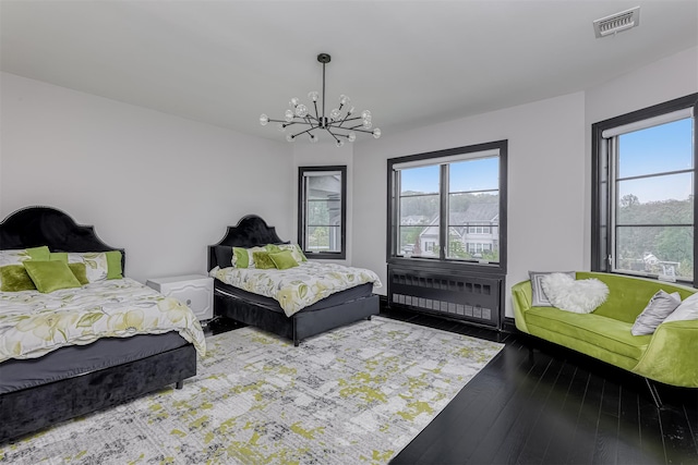 bedroom with radiator heating unit, a chandelier, and wood-type flooring