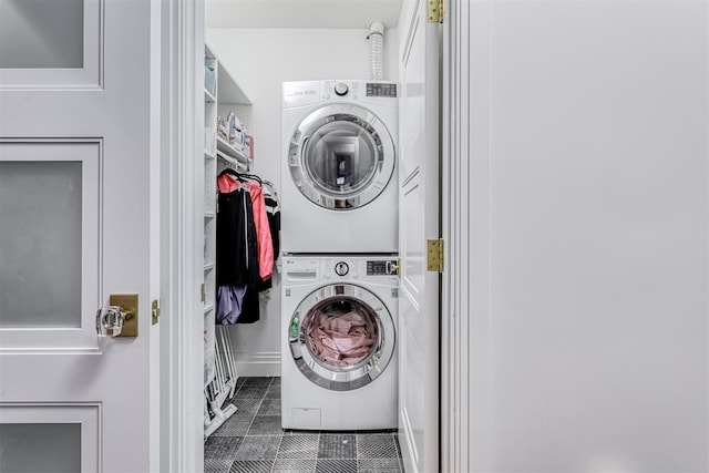 laundry area with stacked washing machine and dryer and tile patterned flooring