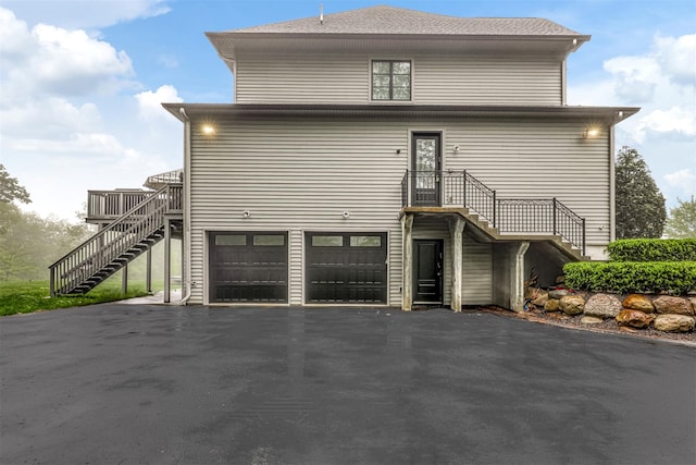 view of front facade featuring stairway, asphalt driveway, and an attached garage
