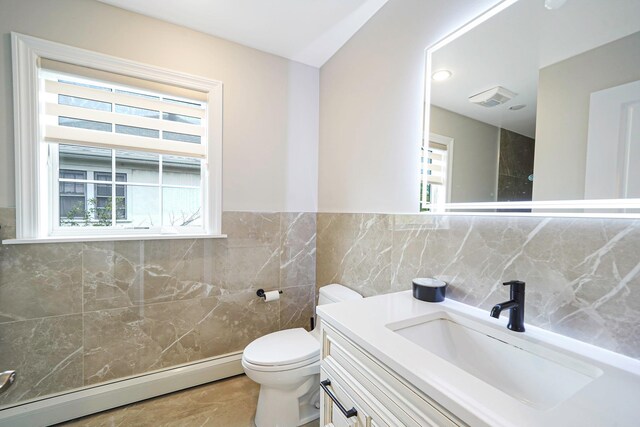 345 Washington Ave, Cedarhurst, NY 11516 - bathroom featuring a baseboard heating unit, tile walls, vanity, toilet, and a wainscoted wall