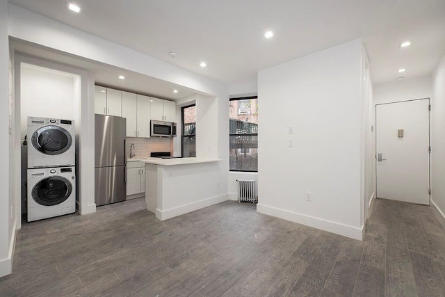 370 Rutland Rd, Brooklyn, NY 11225 - kitchen featuring appliances with stainless steel finishes, stacked washing machine and dryer, radiator heating unit, light countertops, and wood finished floors