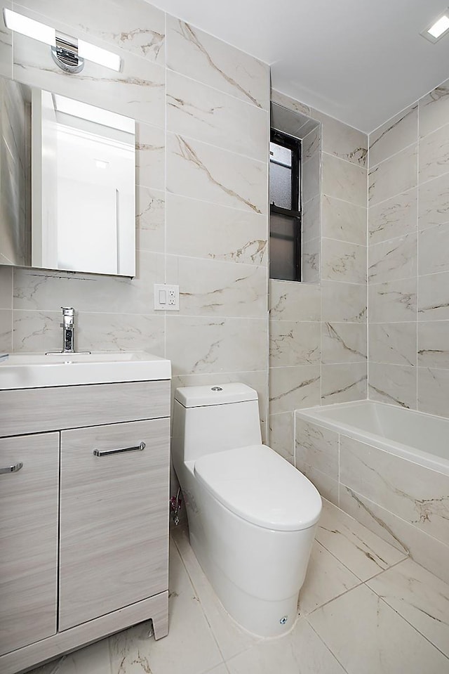 370 Rutland Rd, Brooklyn, NY 11225 - bathroom featuring marble finish floors, tile walls, vanity, and a tub