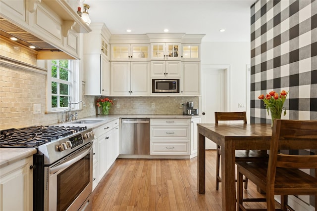 58 Garden St, Garden City, NY 11530 - kitchen featuring appliances with stainless steel finishes, light countertops, light wood-style flooring, white cabinetry, and premium range hood