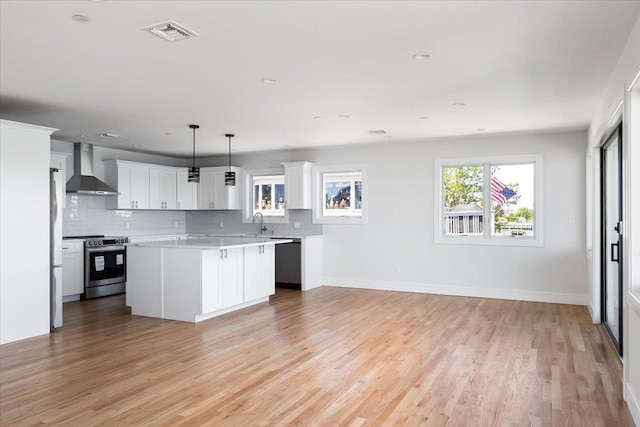12 Pershing Pl, Island Park, NY 11558 - kitchen featuring wall chimney range hood, stainless steel appliances, light countertops, light wood-type flooring, and decorative backsplash