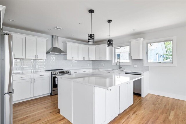 12 Pershing Pl, Island Park, NY 11558 - kitchen featuring wall chimney range hood, stainless steel appliances, light countertops, backsplash, and white cabinets