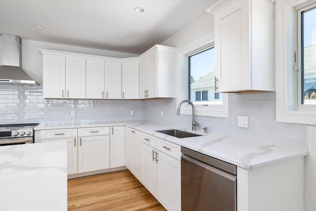 12 Pershing Pl, Island Park, NY 11558 - kitchen with wall chimney exhaust hood, appliances with stainless steel finishes, healthy amount of natural light, and white cabinets