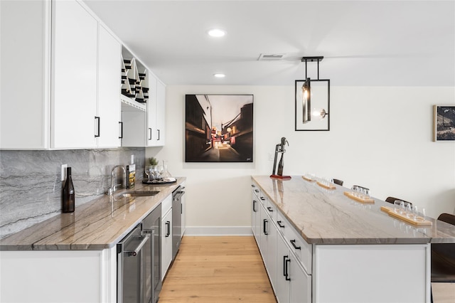 3502 Bennington Dr Unit 113, Fishkill, NY 12524 - kitchen featuring a sink, a peninsula, baseboards, light wood-type flooring, and white cabinets