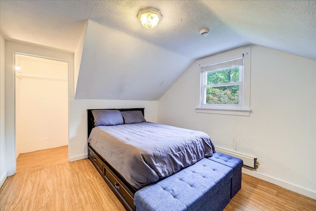 18 Gerow Ln, Cornwall, NY 12553 - bedroom with a baseboard radiator, light wood-style flooring, lofted ceiling, a textured ceiling, and baseboards