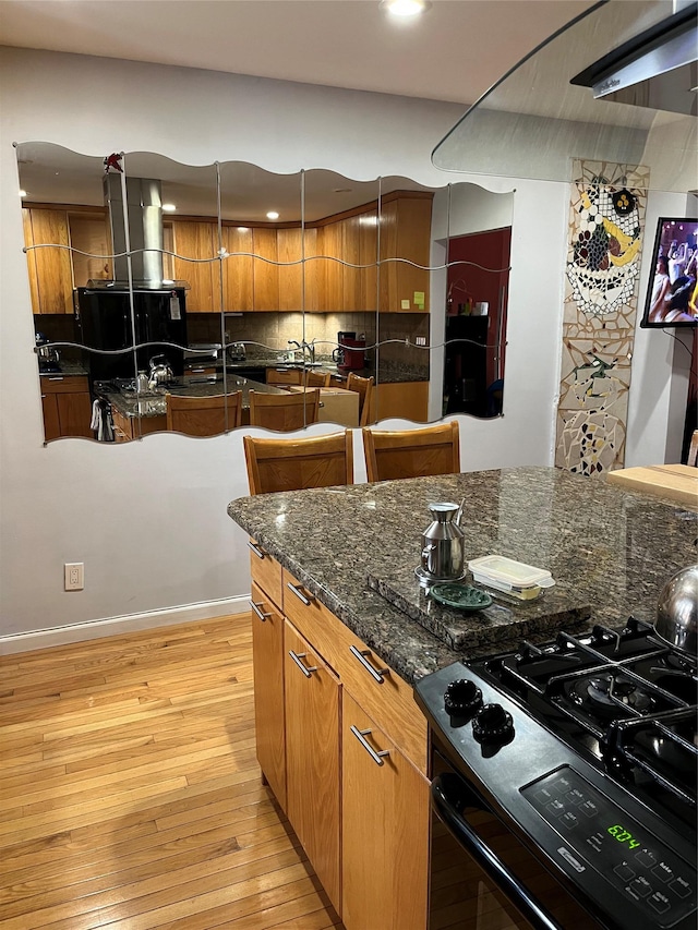 3339 Kingsland Ave, Bronx, NY 10469 - kitchen featuring brown cabinetry, wall chimney exhaust hood, light wood-style floors, range with gas cooktop, and recessed lighting