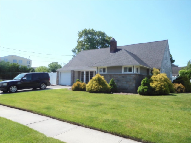 9 Adams St, East Rockaway, NY 11518 - view of front of property with an attached garage, a front lawn, a chimney, driveway, and stone siding