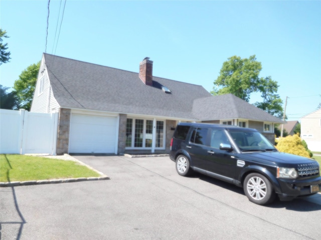 9 Adams St, East Rockaway, NY 11518 - view of front of property featuring an attached garage, asphalt driveway, a chimney, and a shingled roof