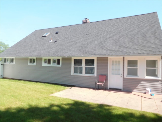 9 Adams St, East Rockaway, NY 11518 - rear view of property featuring roof with shingles, a chimney, a patio area, and a lawn