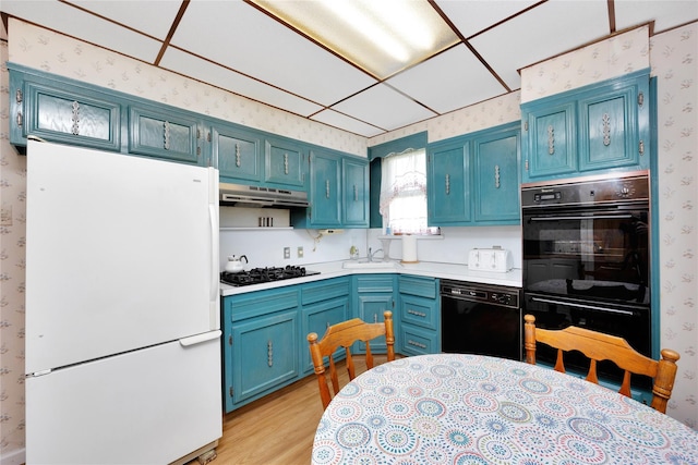 13325 120th St, South Ozone Park, NY 11420 - kitchen featuring black appliances, wallpapered walls, blue cabinetry, under cabinet range hood, and light countertops