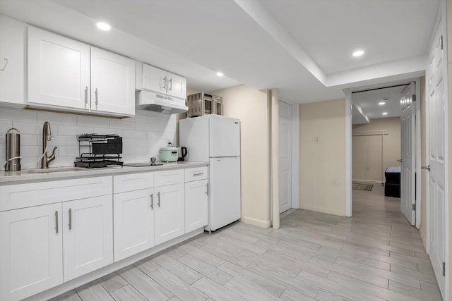 4360 Auburndale Ln, Flushing, NY 11358 - kitchen with under cabinet range hood, freestanding refrigerator, light countertops, tasteful backsplash, and white cabinetry