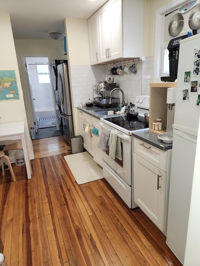 4360 Auburndale Ln, Flushing, NY 11358 - kitchen featuring white appliances, white cabinets, tasteful backsplash, light wood-style floors, and dark countertops