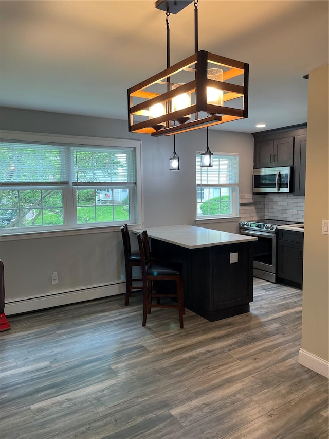 701 Towne House Vlg Unit 701, Hauppauge, NY 11749 - kitchen with appliances with stainless steel finishes, baseboard heating, decorative backsplash, wood finished floors, and hanging light fixtures