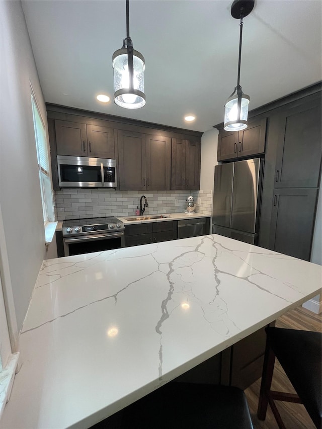 701 Towne House Vlg Unit 701, Hauppauge, NY 11749 - kitchen featuring stainless steel appliances, a sink, tasteful backsplash, dark brown cabinetry, and pendant lighting