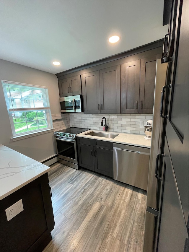 701 Towne House Vlg Unit 701, Hauppauge, NY 11749 - kitchen featuring stainless steel appliances, a sink, light wood-style floors, light stone counters, and backsplash