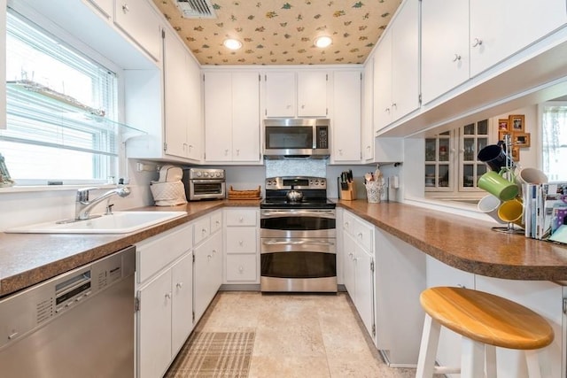 12 Hazel Pl, Woodmere, NY 11598 - kitchen featuring stainless steel appliances, white cabinetry, recessed lighting, and a kitchen breakfast bar