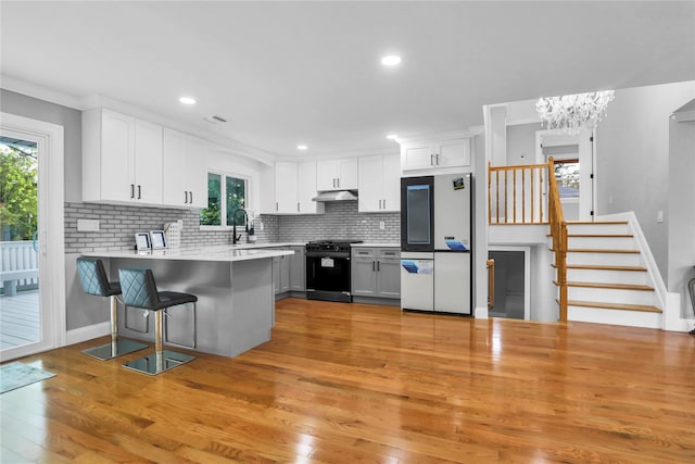 236 Martin Dr, Syosset, NY 11791 - kitchen featuring white refrigerator, range with gas stovetop, plenty of natural light, a peninsula, and recessed lighting