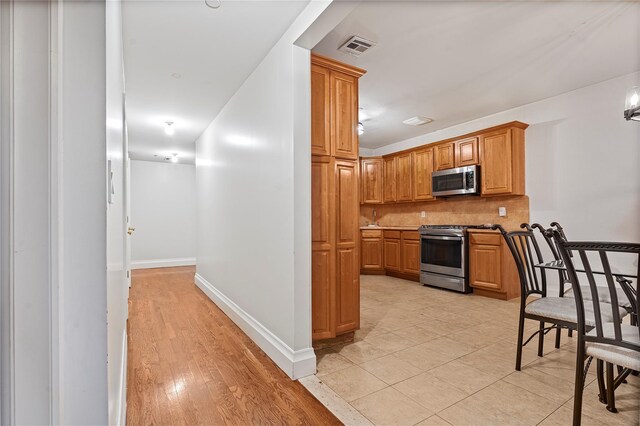 218 Middleton St Unit Apt6Rooftop, Brooklyn, NY 11206 - kitchen with stainless steel appliances, backsplash, baseboards, brown cabinets, and light wood finished floors