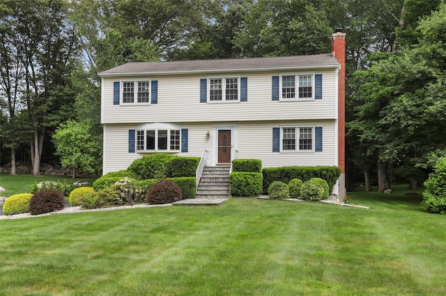 16 Shipley Dr, Cortlandt Manor, NY 10567 - colonial-style house featuring a chimney, a front lawn, and view of scattered trees