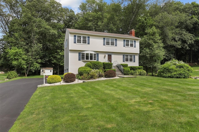 16 Shipley Dr, Cortlandt Manor, NY 10567 - colonial home featuring a chimney, a front lawn, view of scattered trees, and asphalt driveway
