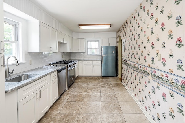 99 Roosevelt Ct, Carle Place, NY 11514 - kitchen featuring stainless steel appliances, a sink, wallpapered walls, light stone countertops, and decorative backsplash