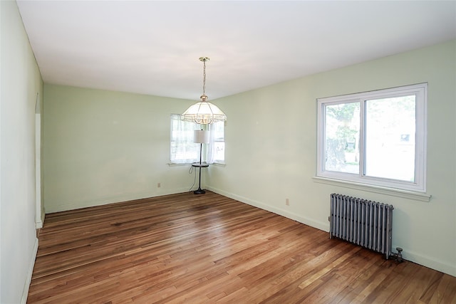 99 Roosevelt Ct, Carle Place, NY 11514 - spare room with radiator heating unit, light wood finished floors, a chandelier, and baseboards