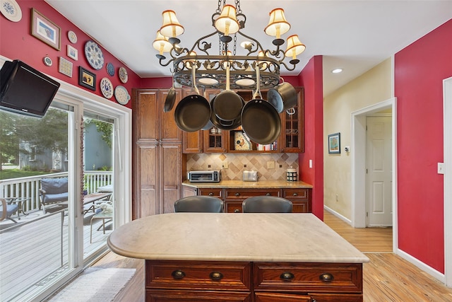 1771 Hanover St, Yorktown Heights, NY 10598 - kitchen featuring a chandelier, light wood-type flooring, backsplash, light countertops, and glass insert cabinets