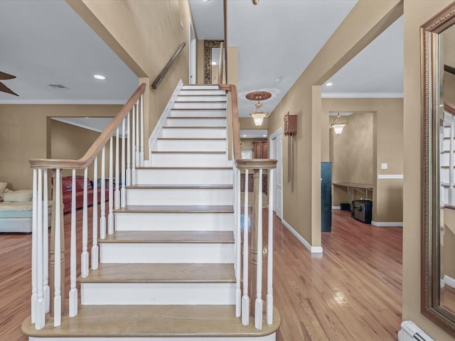 1674 Birch Dr, Merrick, NY 11566 - stairs featuring a baseboard heating unit, ornamental molding, wood finished floors, baseboards, and a ceiling fan