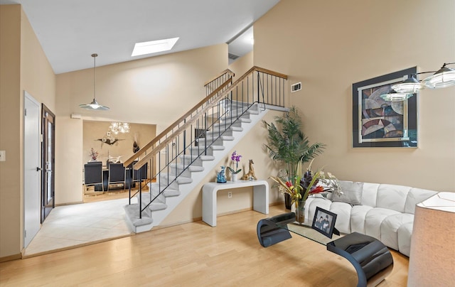 34 Oak Meadow Rd, Commack, NY 11725 - living area with stairs, wood finished floors, high vaulted ceiling, a skylight, and a chandelier