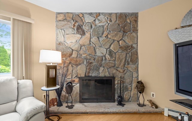 34 Oak Meadow Rd, Commack, NY 11725 - living area with a baseboard heating unit, healthy amount of natural light, a fireplace, and wood finished floors