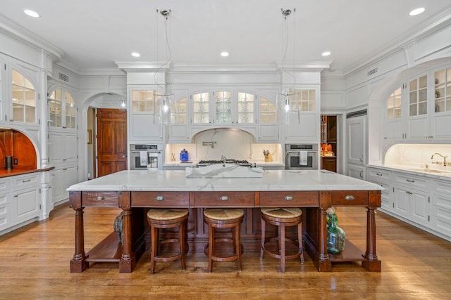 7 Fox Meadow Ln, Lloyd Harbor, NY 11743 - kitchen featuring appliances with stainless steel finishes, white cabinetry, crown molding, a spacious island, and wood finished floors