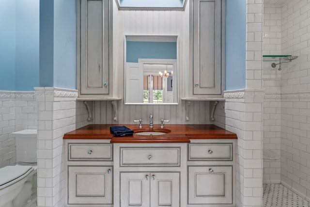 7 Fox Meadow Ln, Lloyd Harbor, NY 11743 - bathroom with wainscoting, vanity, tile walls, tiled shower, and a chandelier