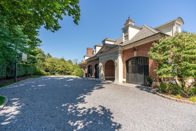 7 Fox Meadow Ln, Lloyd Harbor, NY 11743 - view of property exterior featuring brick siding, driveway, and a chimney